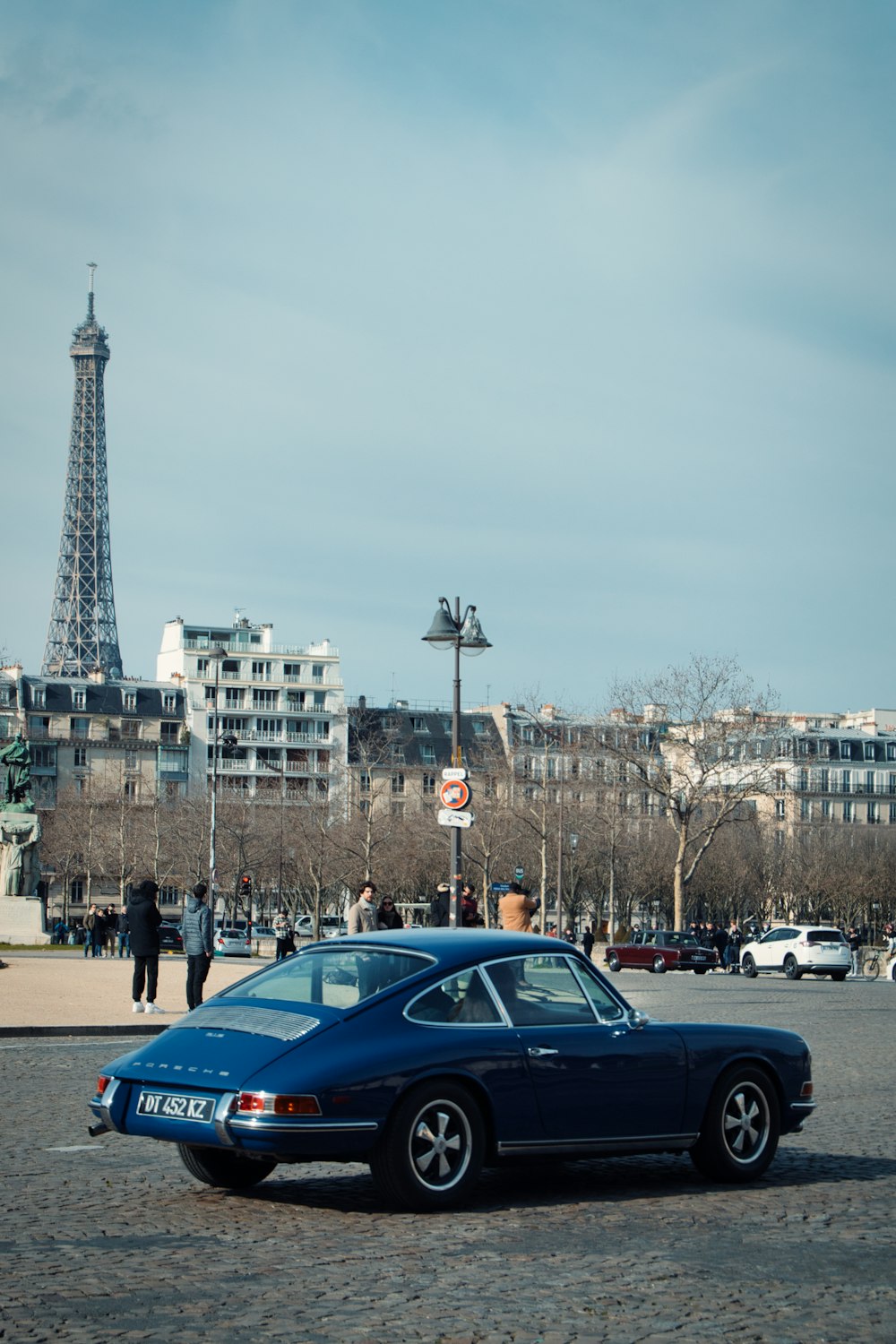 a blue car parked in front of the eiffel tower
