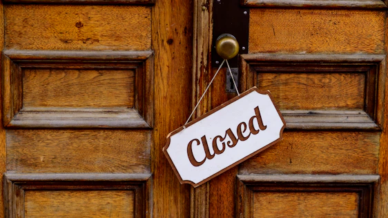 A closed sign hanging on a rustic wooden door symbolizing the website closure.
