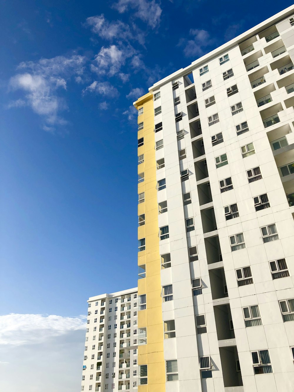 a tall white and yellow building next to a parking lot