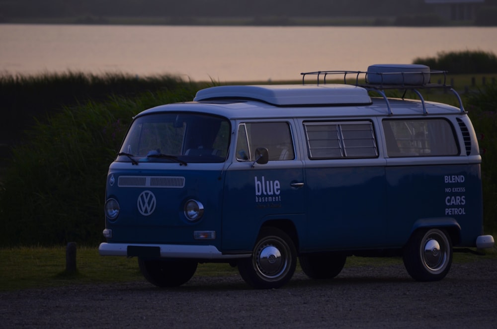 a blue vw bus parked in front of a body of water