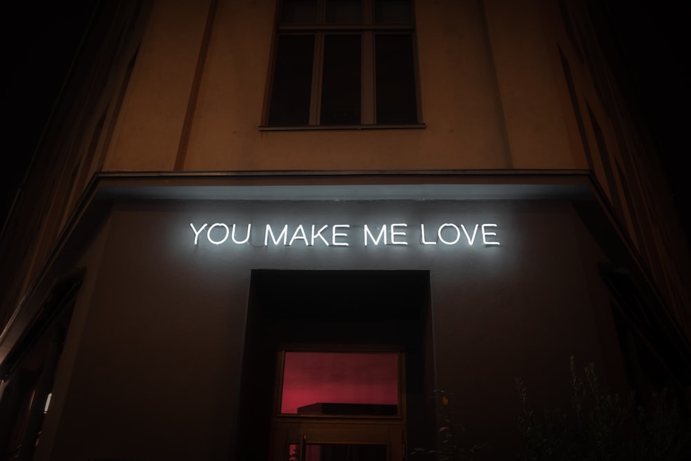 a building with a neon sign that says you make me love