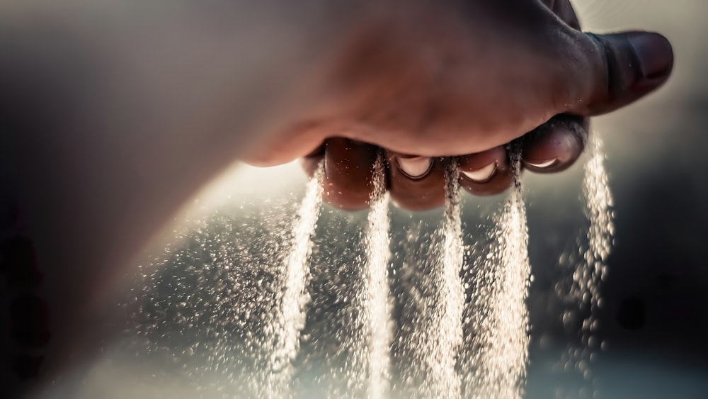 a person's hand sprinkling water from a faucet