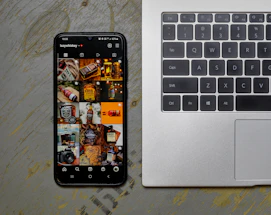 an open laptop computer sitting next to a cell phone