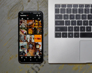 an open laptop computer sitting next to a cell phone