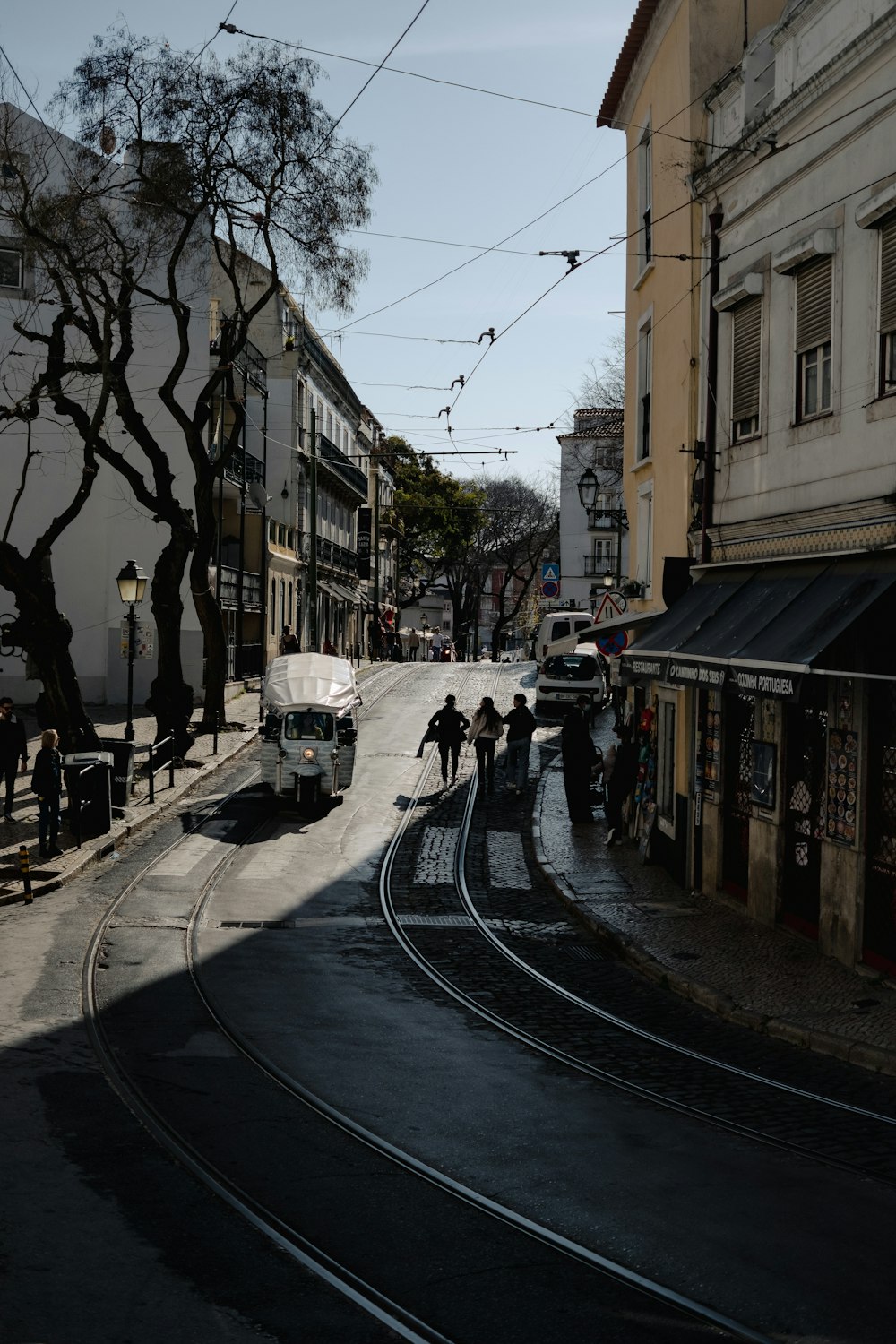 a group of people walking down a street next to a train track