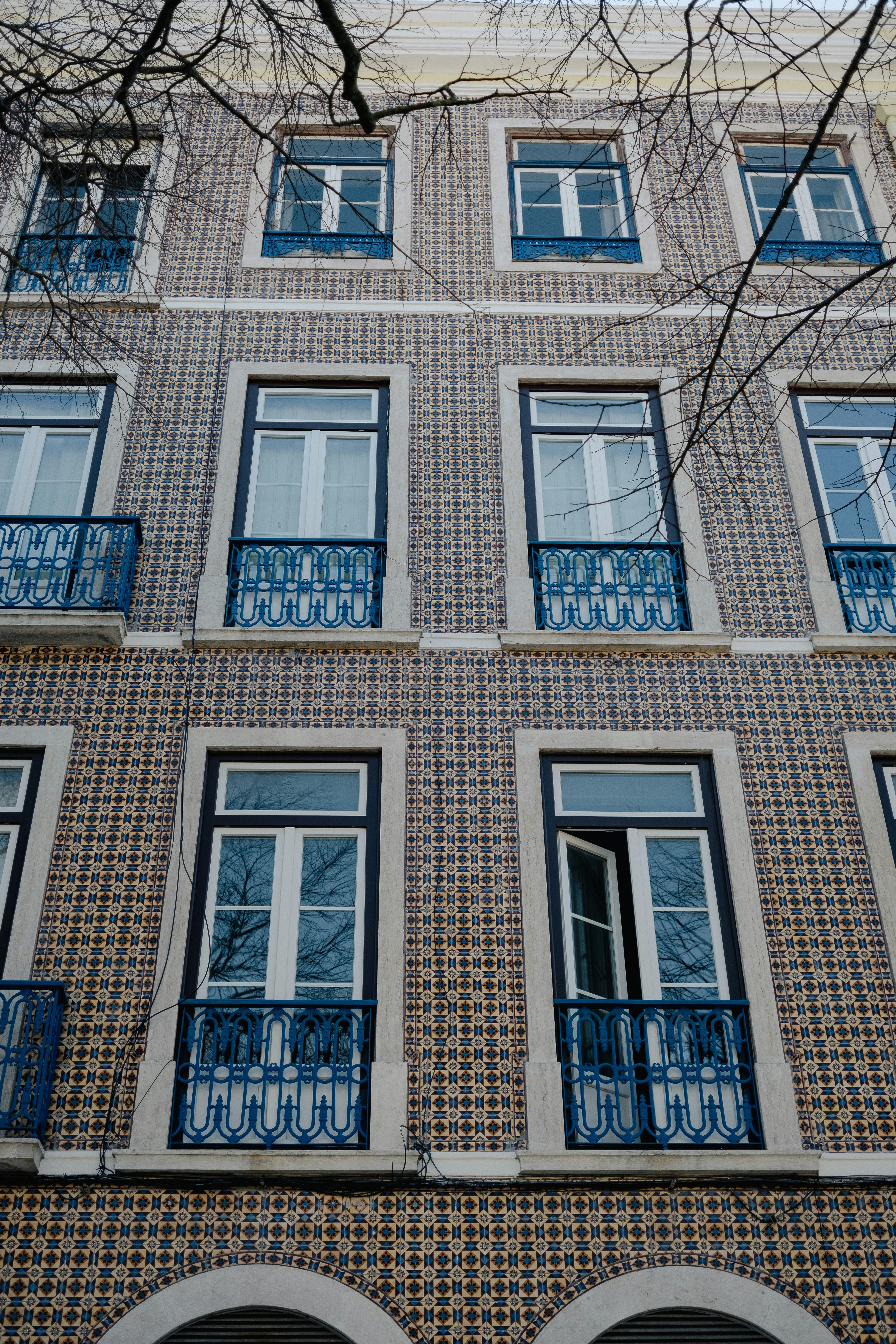 a tall building with many windows and blue balconies