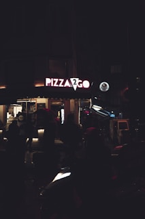 a group of people standing outside of a pizza shop