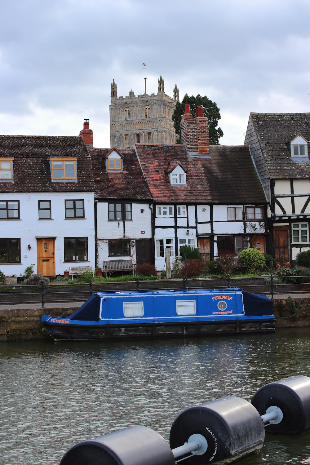 a blue boat floating down a river next to tall buildings