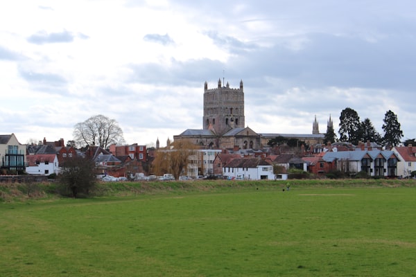 a grassy field in the middle of a town with a church in the background