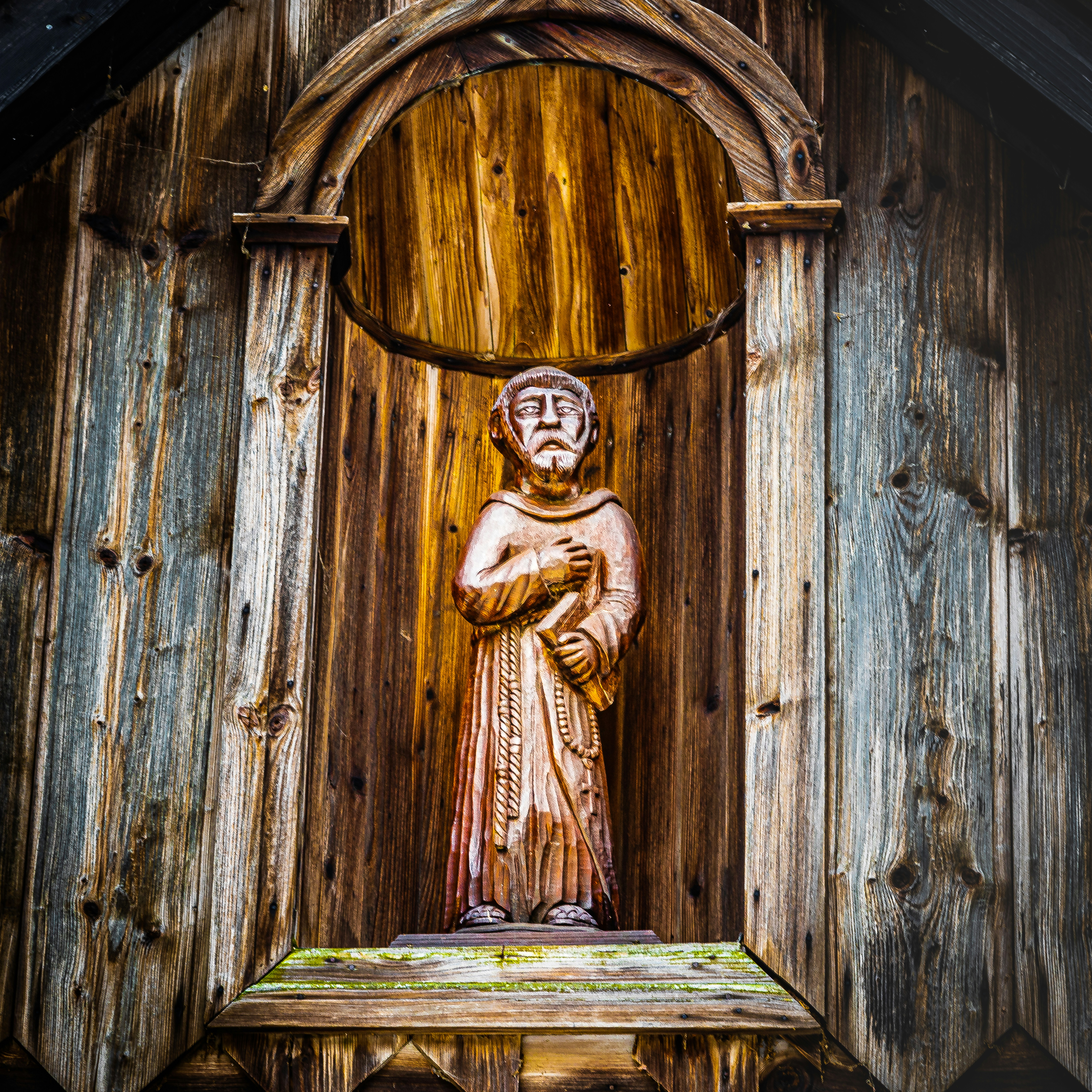 confess: a statue of a person standing in front of a wooden wall