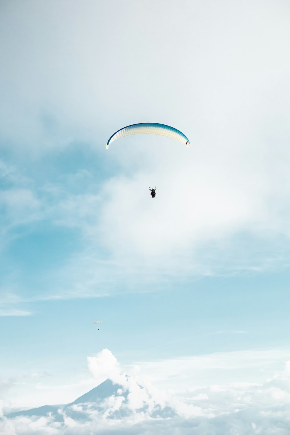 a paraglider is flying high above the clouds