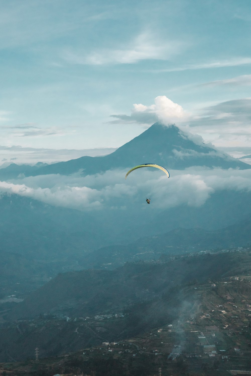 a paraglider flying over a city below a mountain