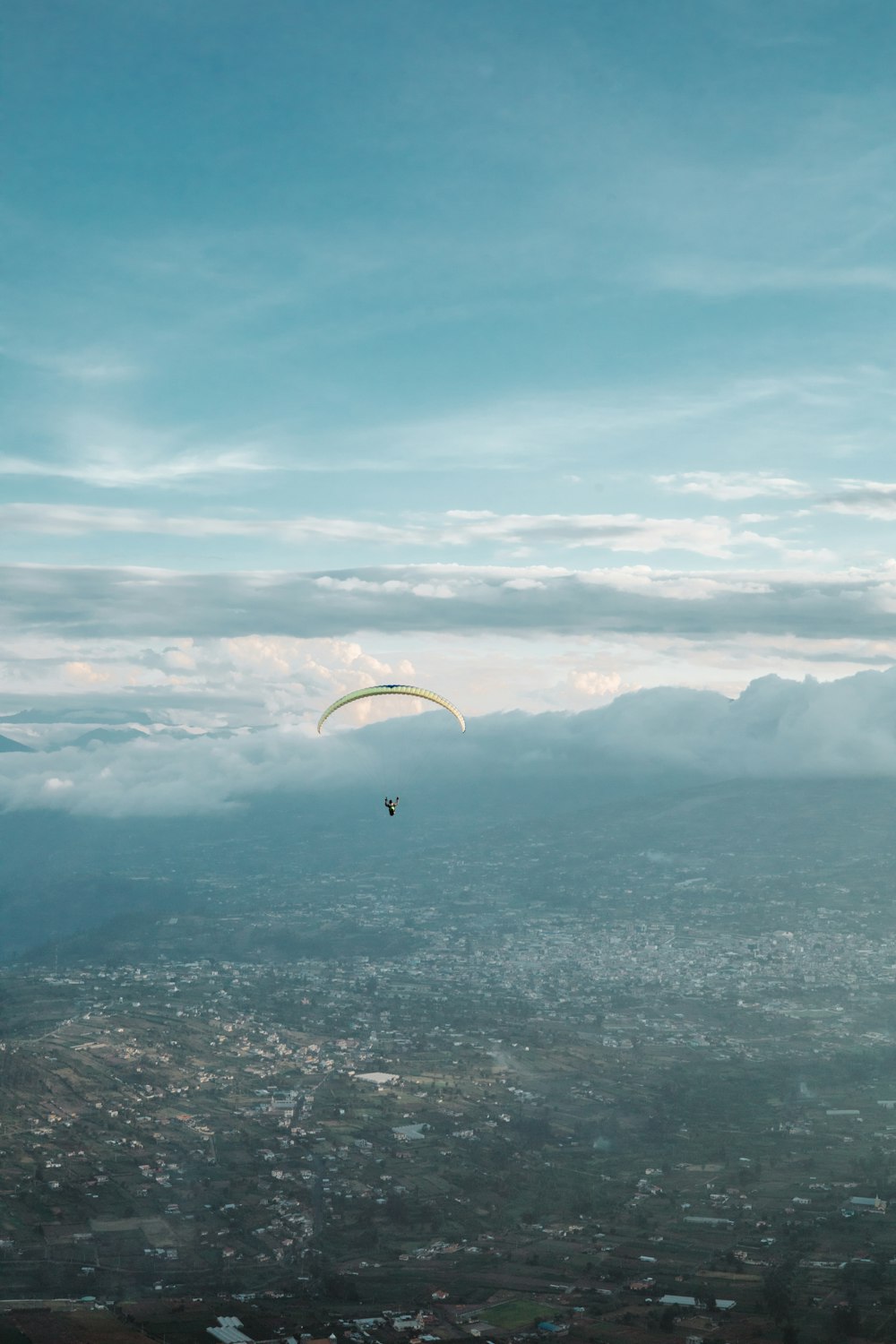 a paraglider flying over a city under a cloudy sky