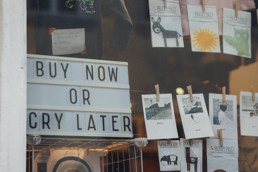 a store window with a sign that says buy now or cry later