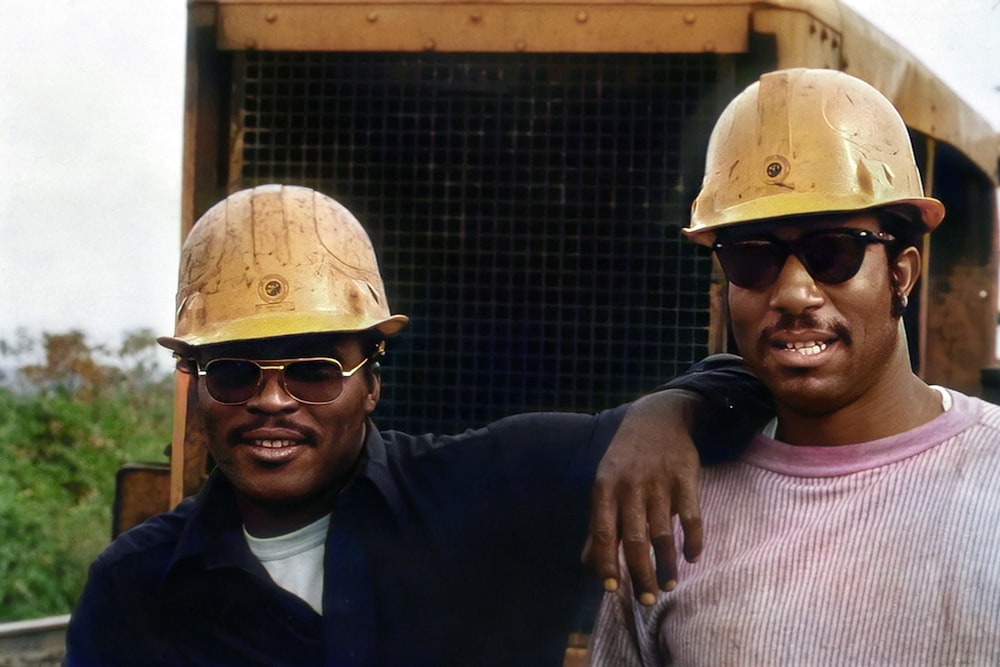 two men wearing hard hats and sunglasses standing next to each other