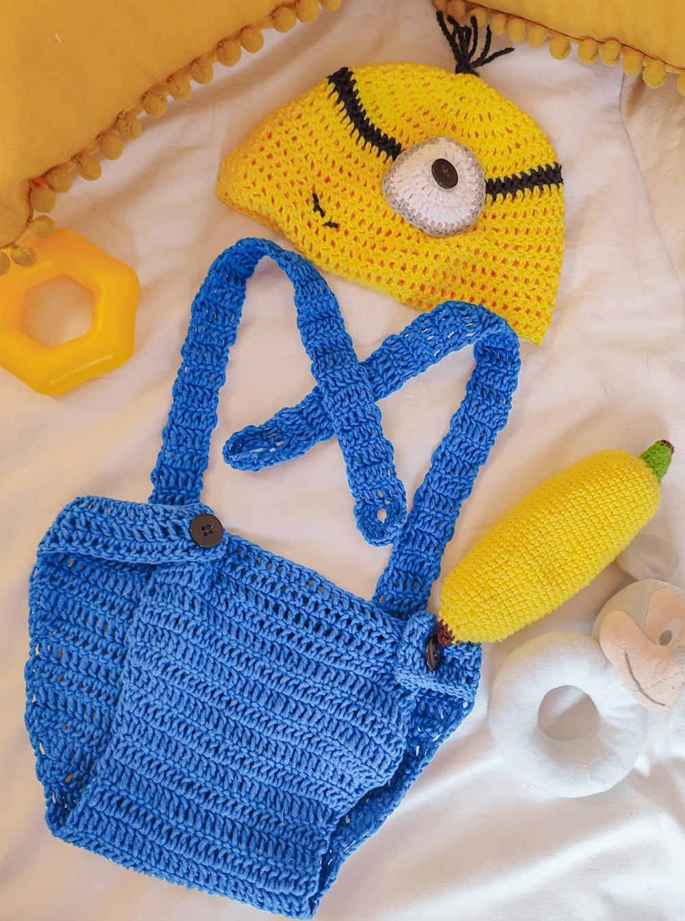 um saco de crochê, banana e chapéu em uma cama