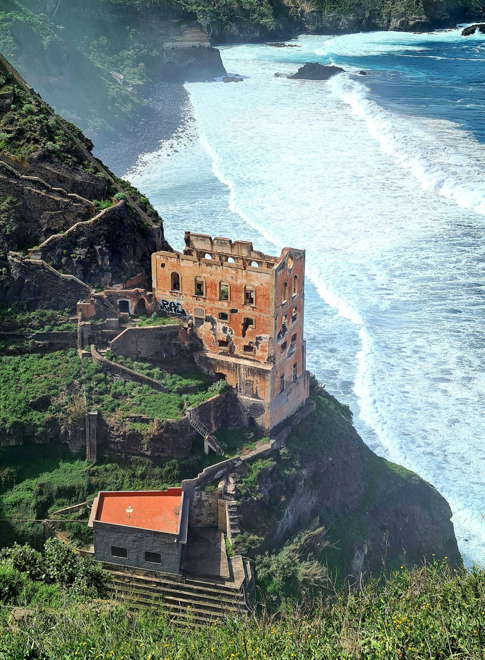 an old building sitting on top of a cliff next to the ocean