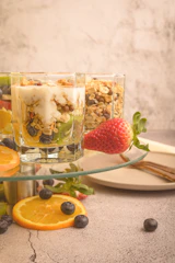 a bowl of granola, orange slices, strawberries, blueberries, and