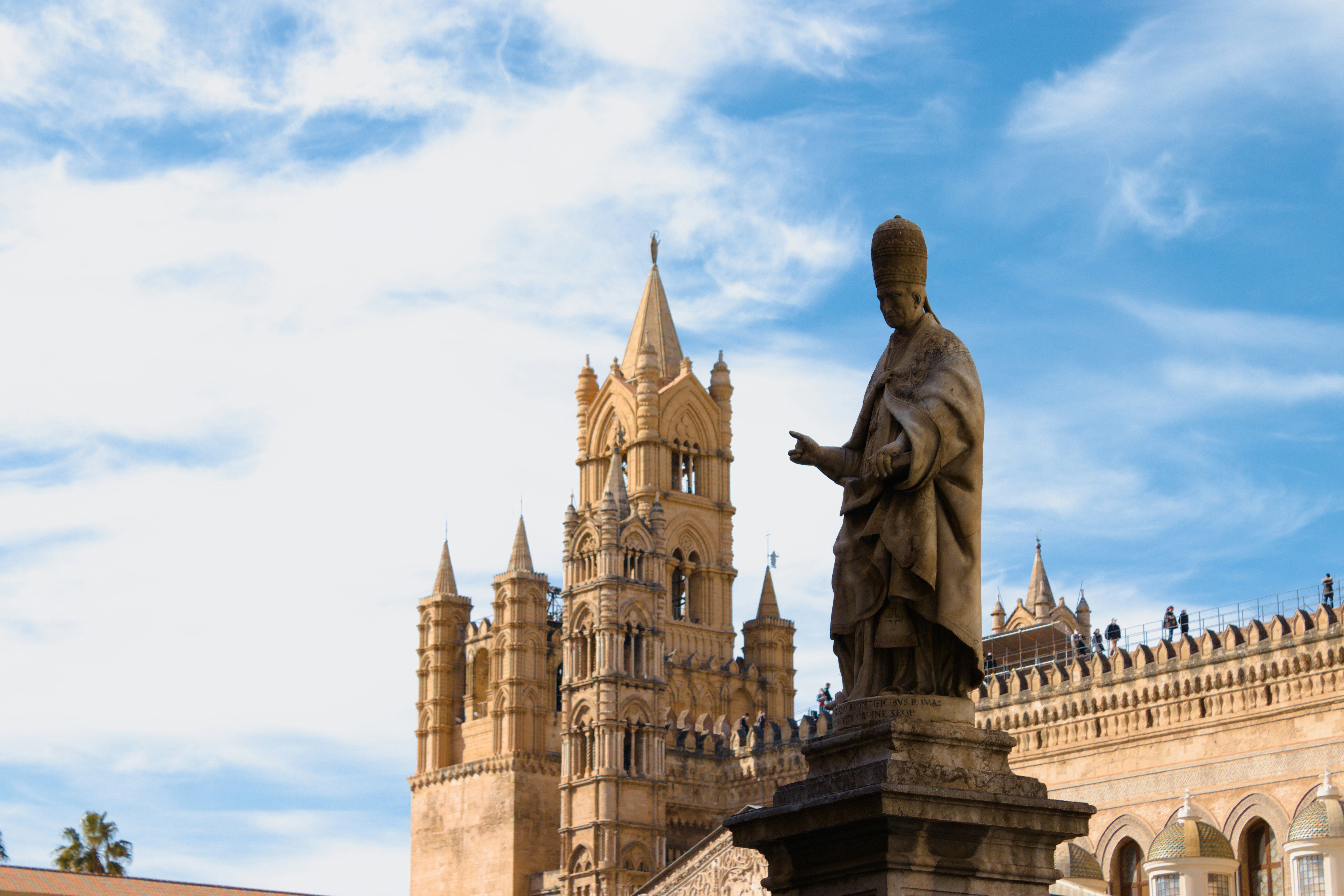 a statue of a monk in front of a castle
