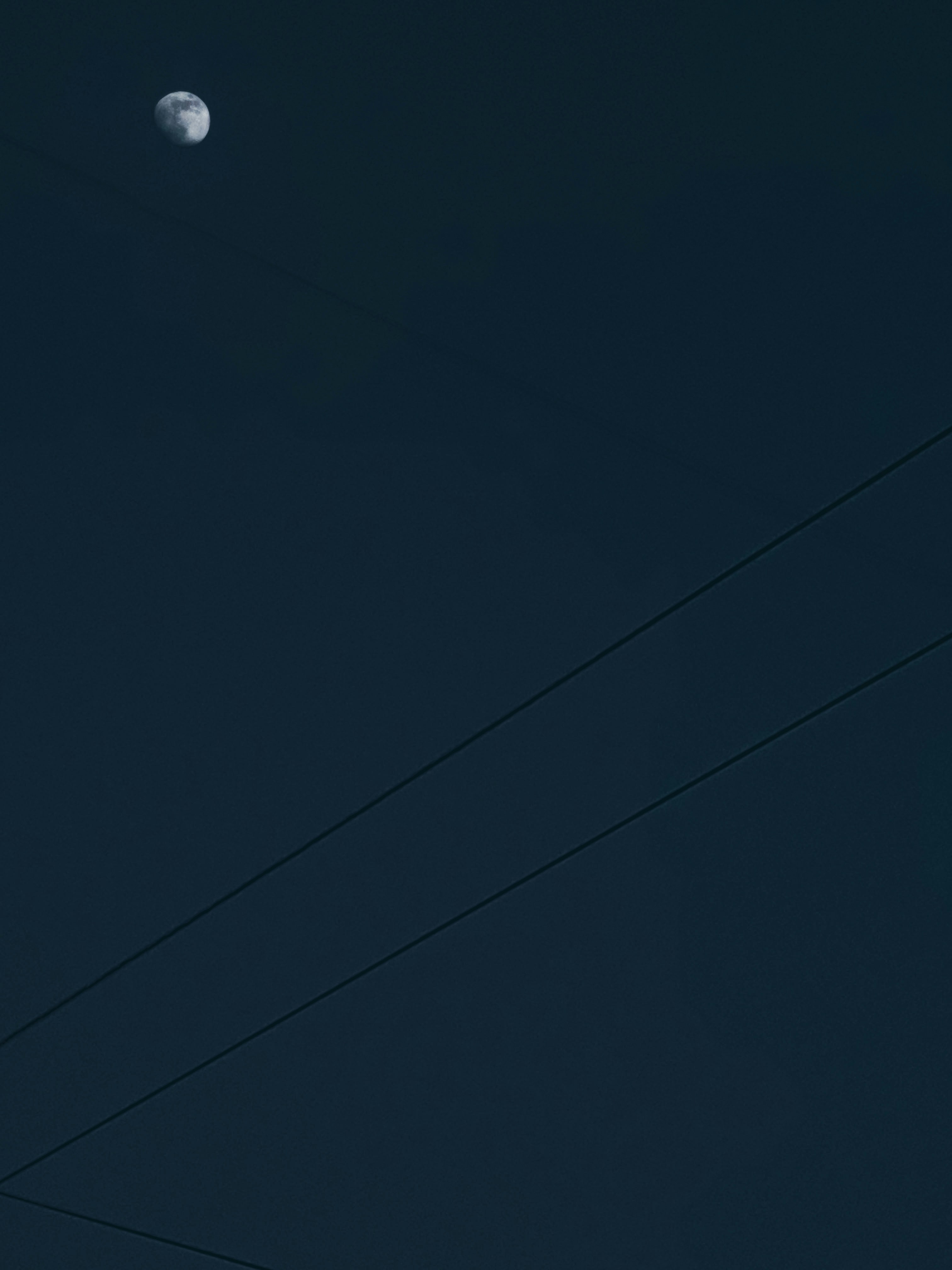a full moon is seen in the sky above power lines