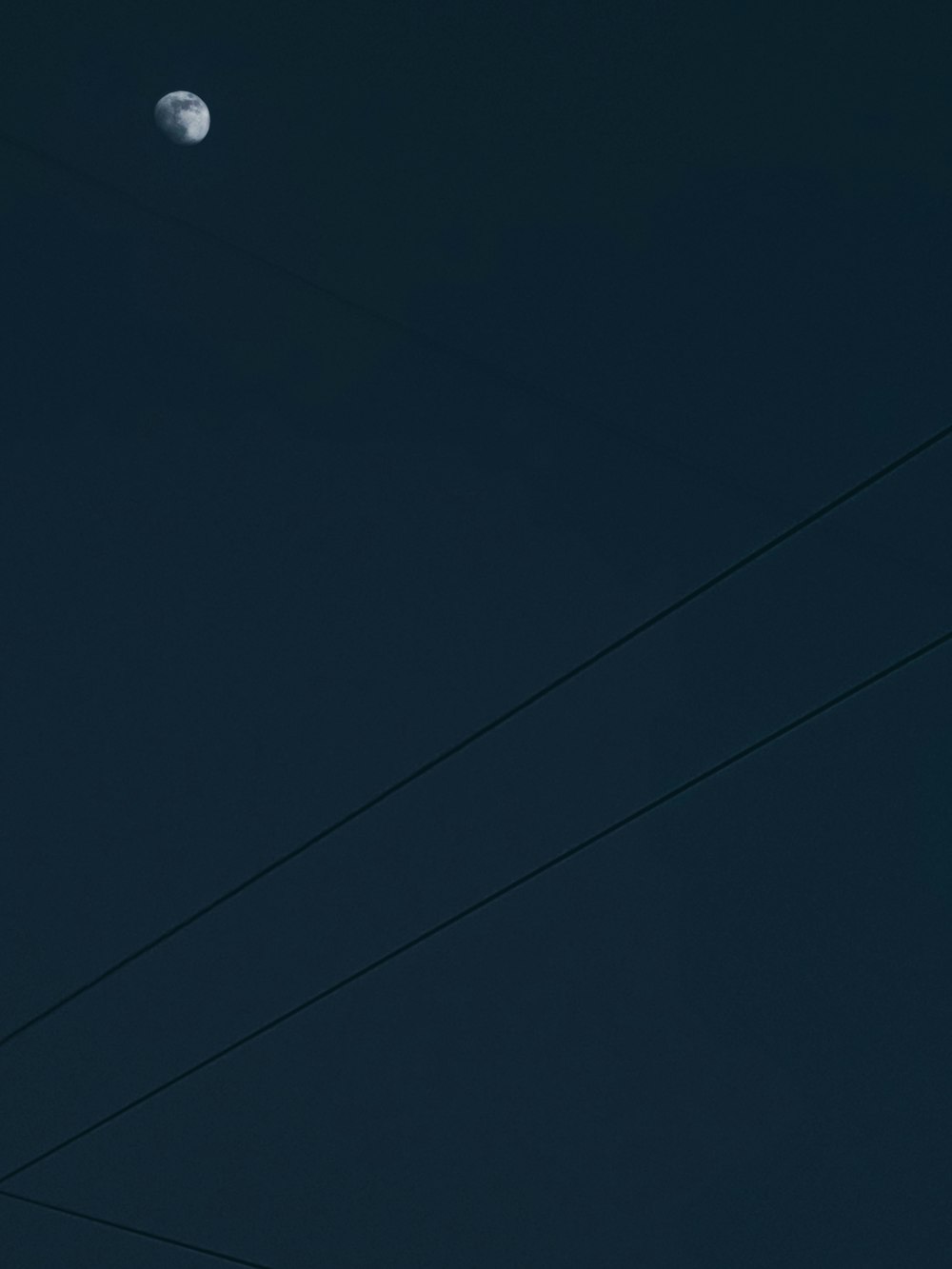 a full moon is seen in the sky above power lines