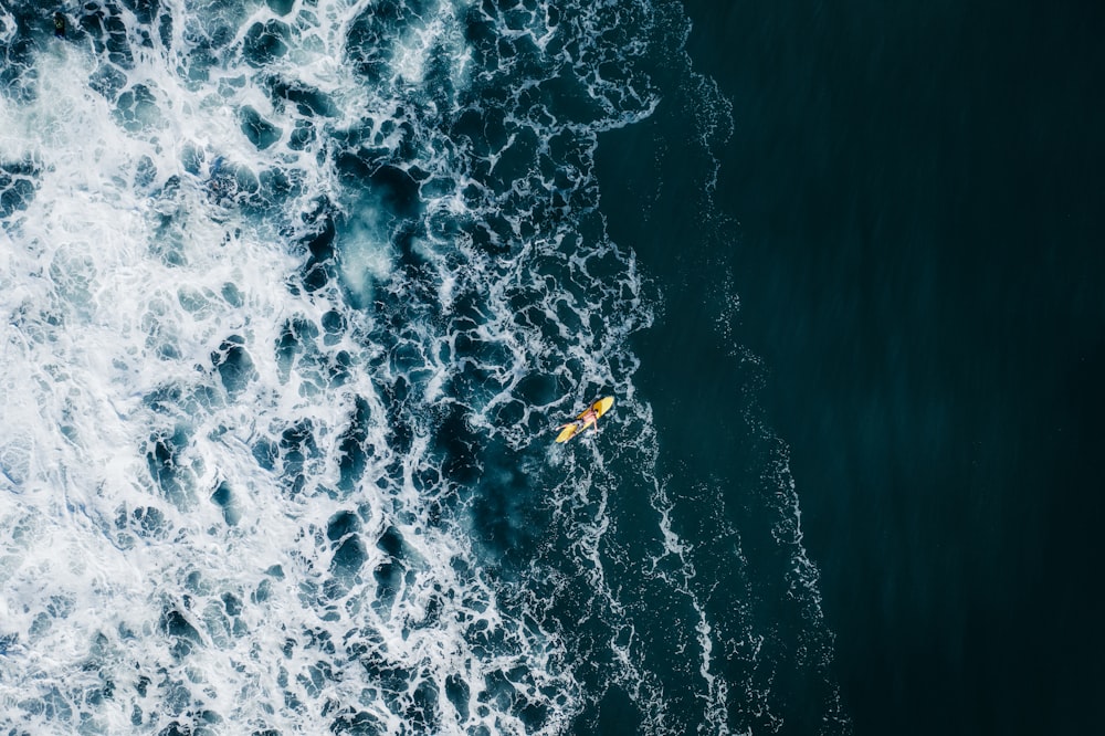 an aerial view of a yellow kayak in the ocean
