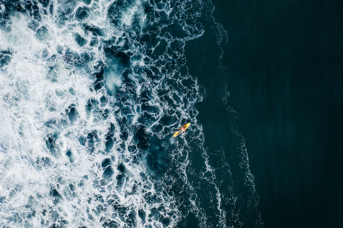 A lone yellow kayak moving through deep coastal water