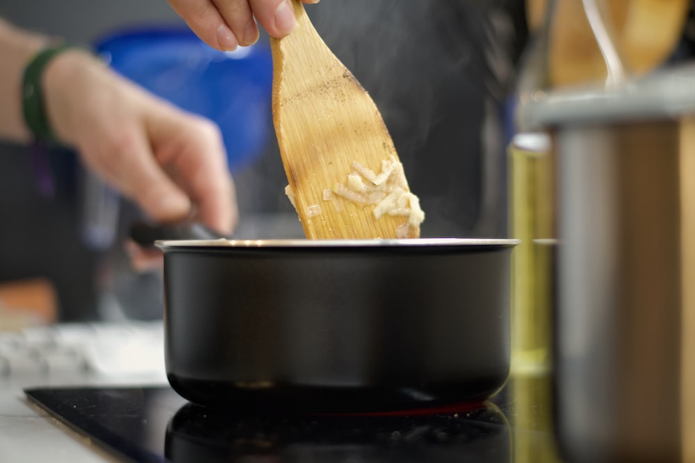 a person stirring a pot with a wooden spoon