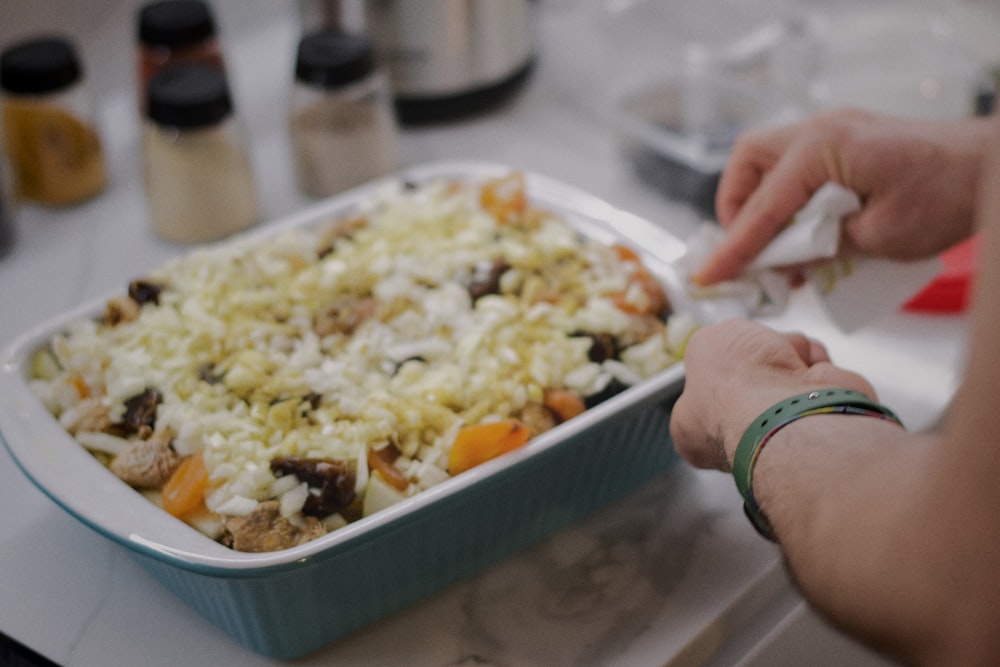 a person putting a piece of food in a casserole dish