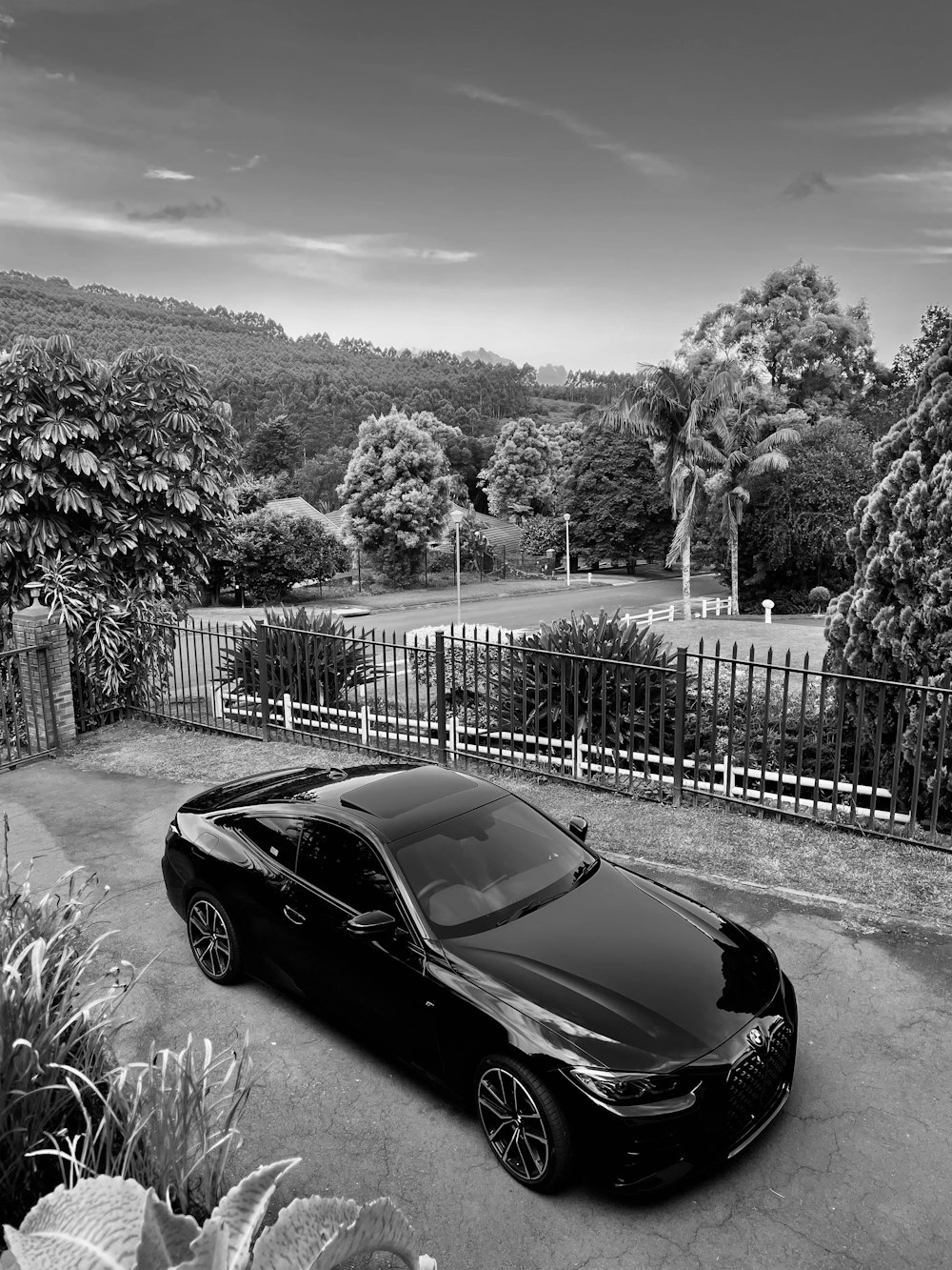 a black car parked in a driveway next to a fence