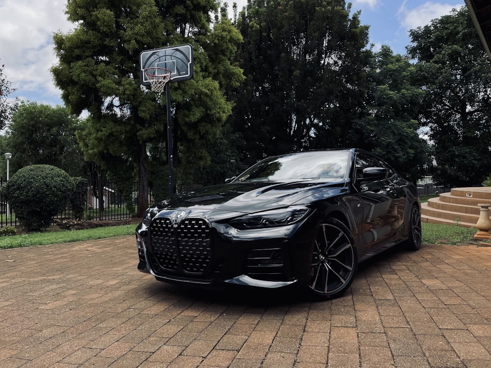 a black sports car parked in front of a basketball hoop
