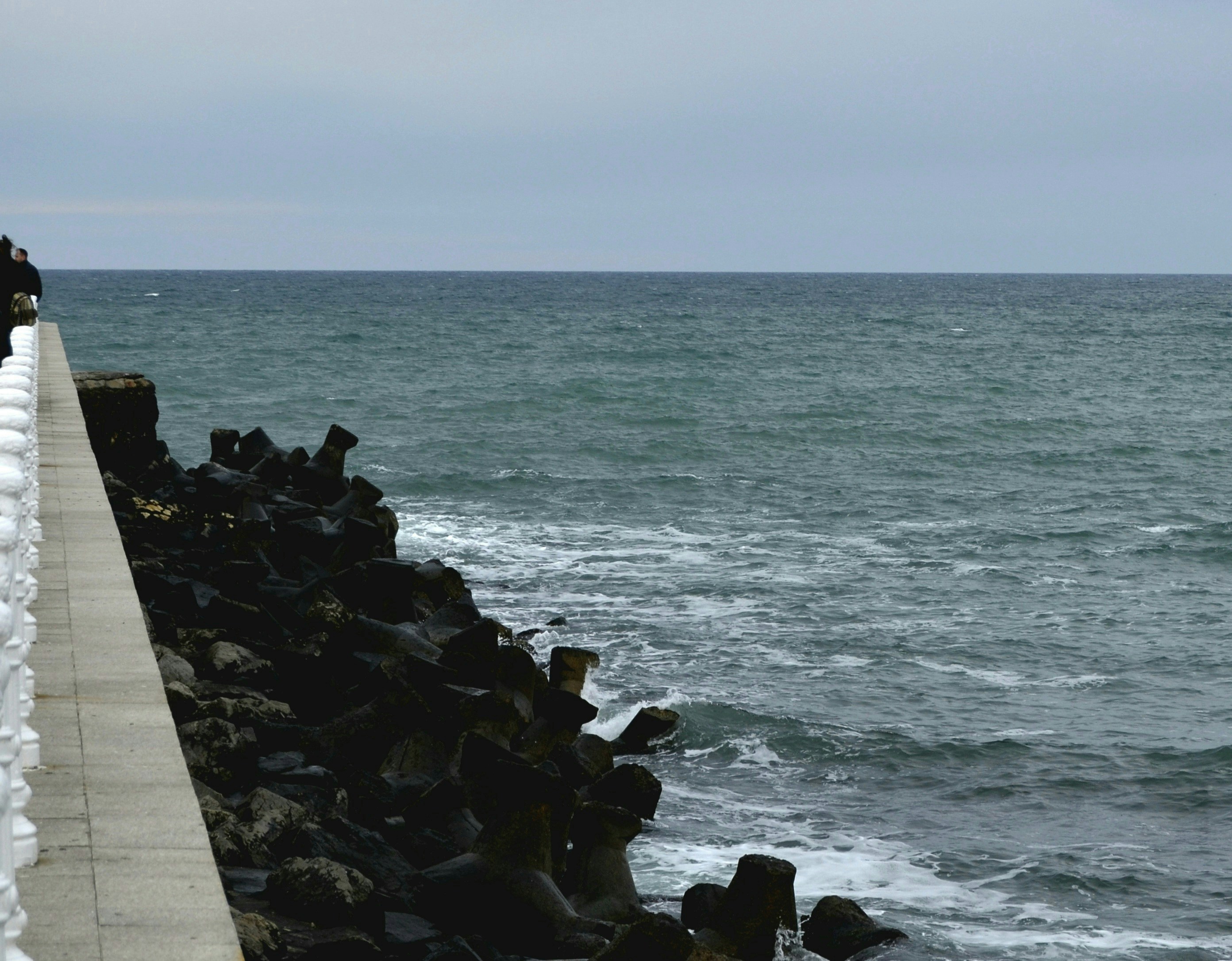 a man walking along a pier next to the ocean