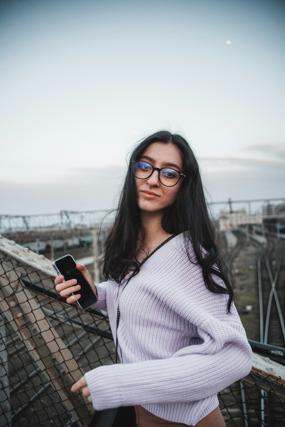 a woman wearing glasses is holding a cell phone