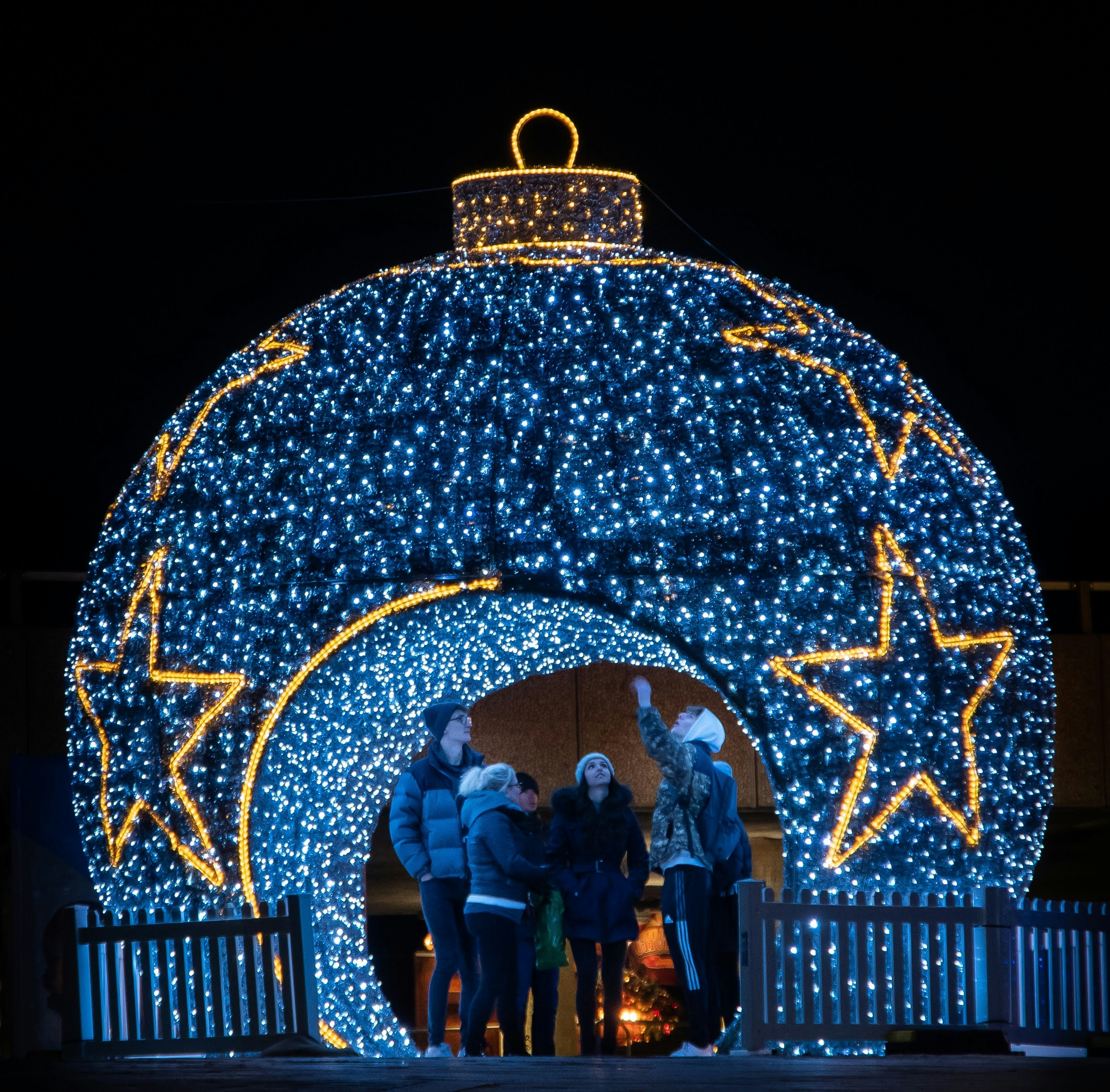 A group of people standing in front of a christmas light display photo ...