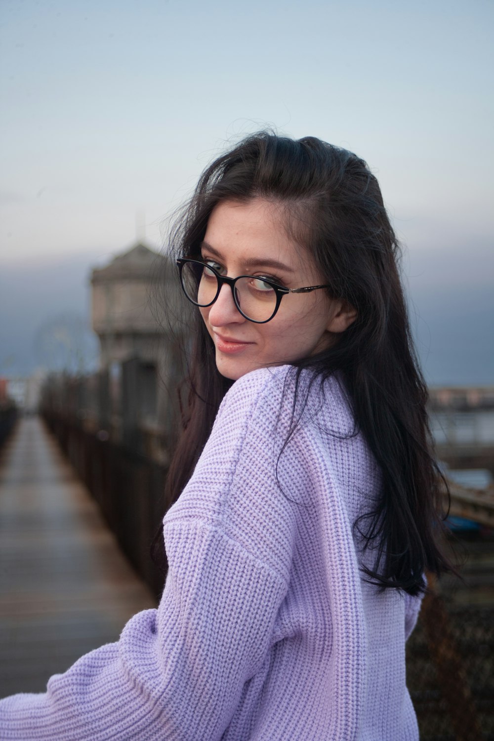 a woman wearing glasses standing on a pier