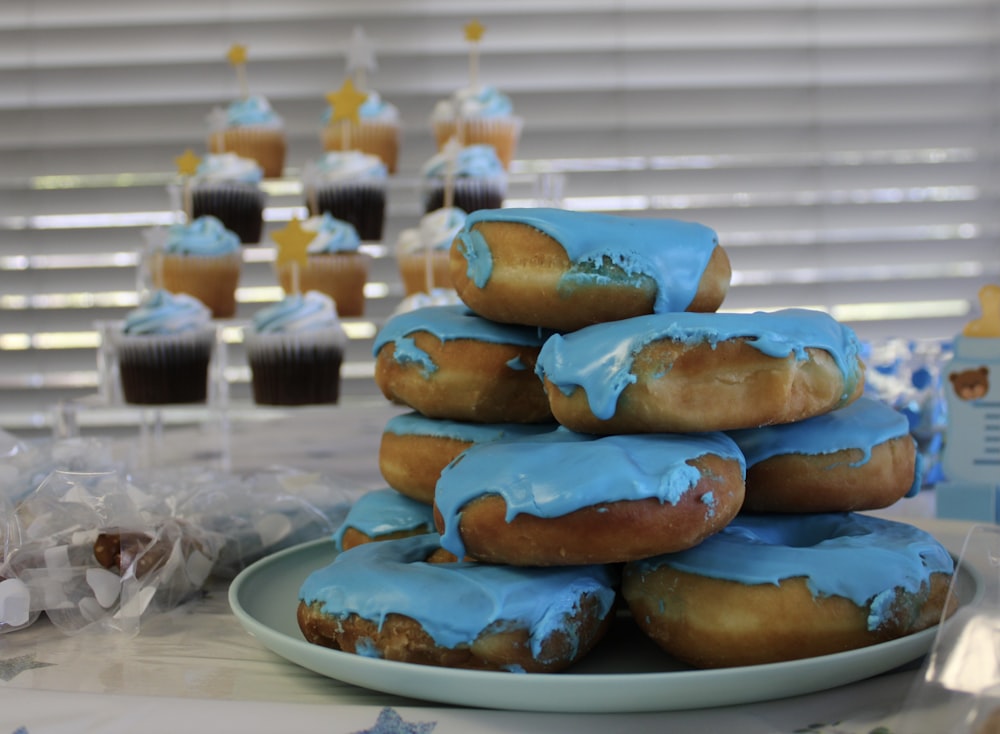 a plate of blue frosted donuts on a table