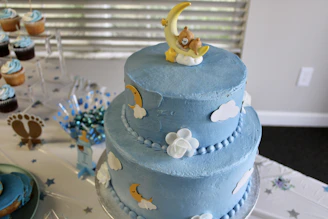 a blue cake with a teddy bear on top of it