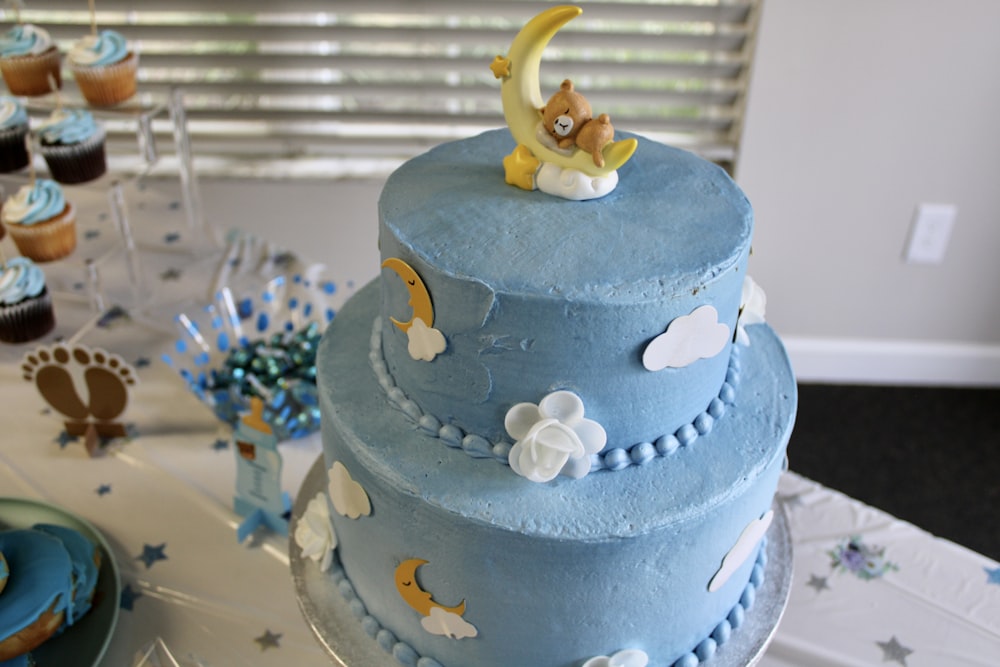 a blue cake with a teddy bear on top of it