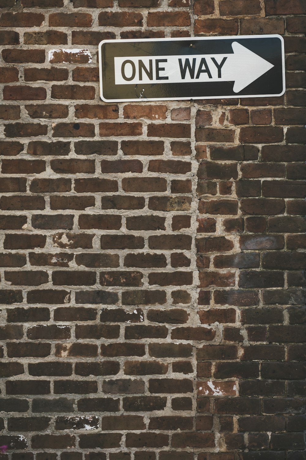 a one way sign on a brick wall