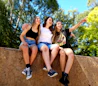 three girls are sitting on a wall and laughing