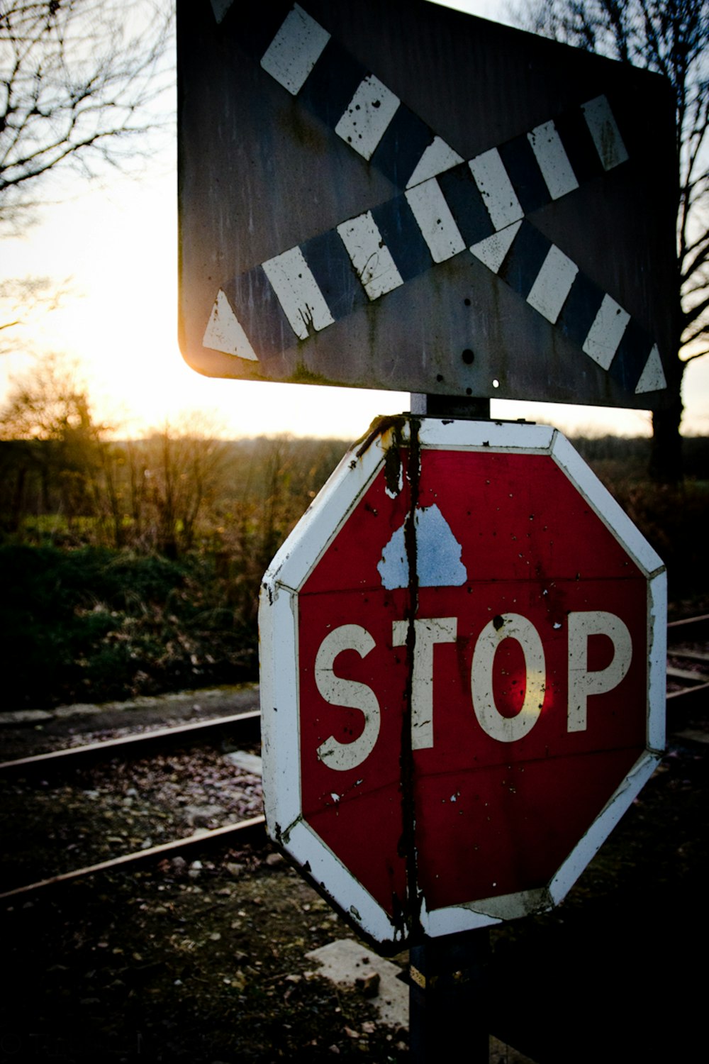 a red stop sign sitting on the side of a train track