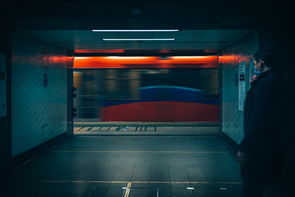 a man standing in a subway station talking on a cell phone