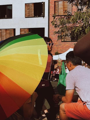 a group of people standing around a colorful umbrella
