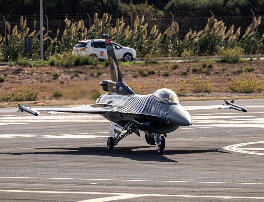 a silver jet sitting on top of an airport runway