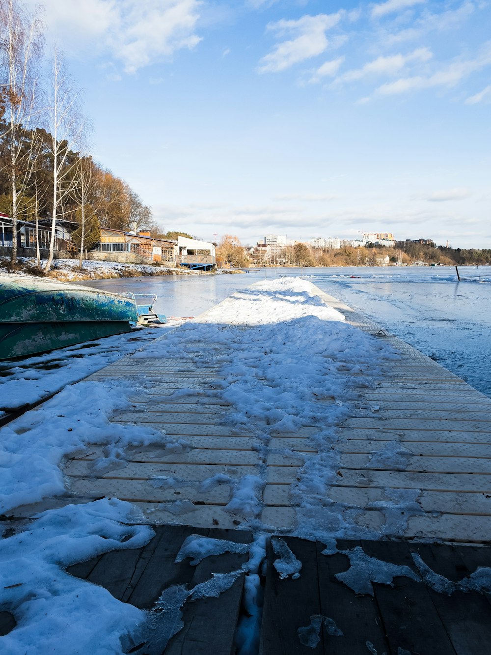 ein mit Schnee bedecktes Holzdock neben einem Gewässer