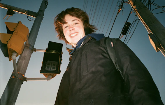 A smiling person standing at a crossroads, looking hopeful toward the horizon.