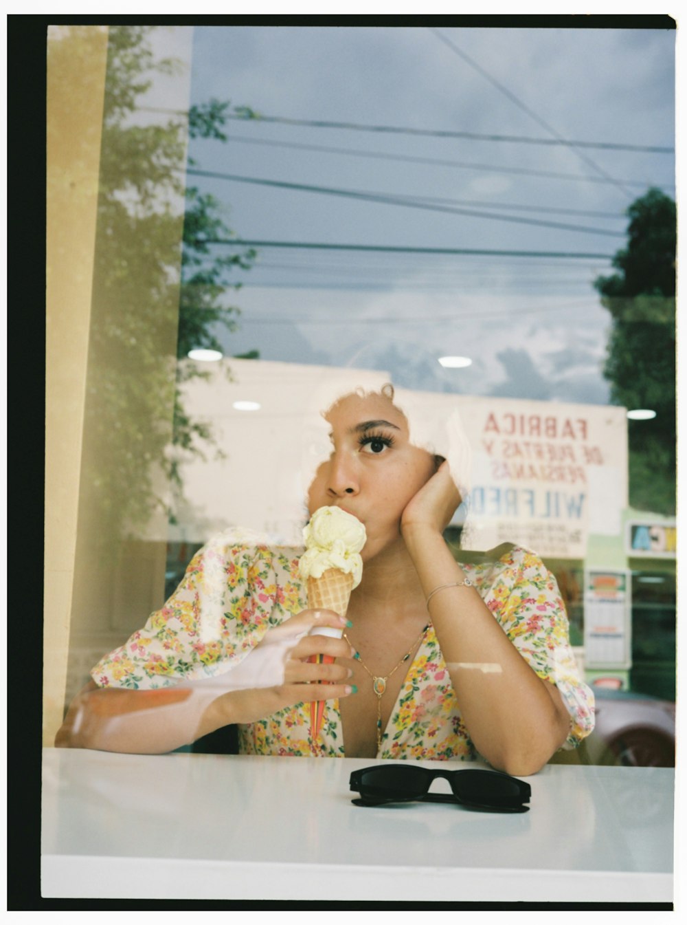 a woman sitting at a table eating an ice cream cone