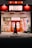 A person walks past a brightly lit karaoke establishment with prominent red signage and illuminated posters in Japanese. The scene takes place at night, with the warm glow of lights enhancing the contrast against the dark street.