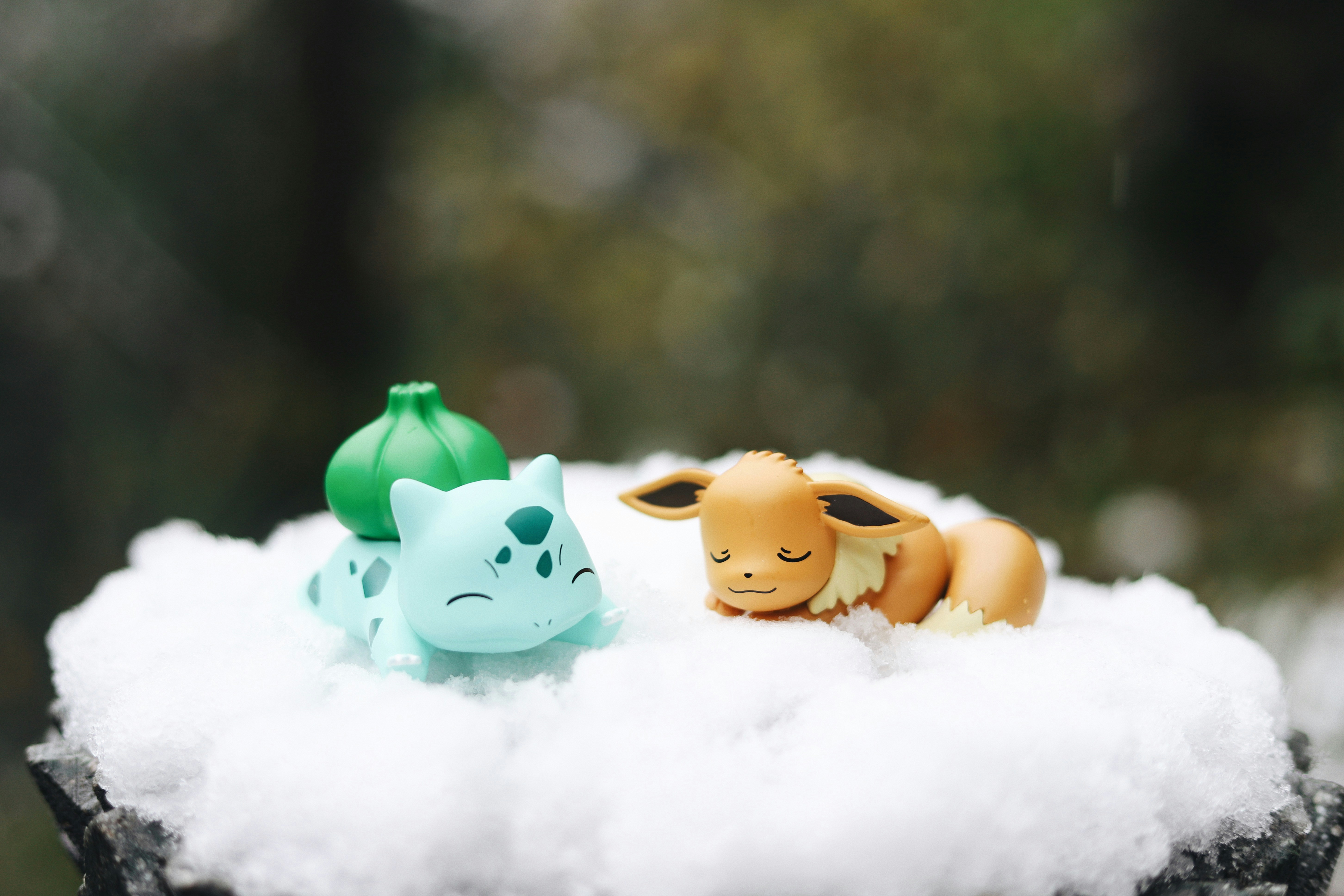 two toy animals sitting on top of a pile of snow