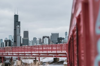 a red bridge with a city in the background